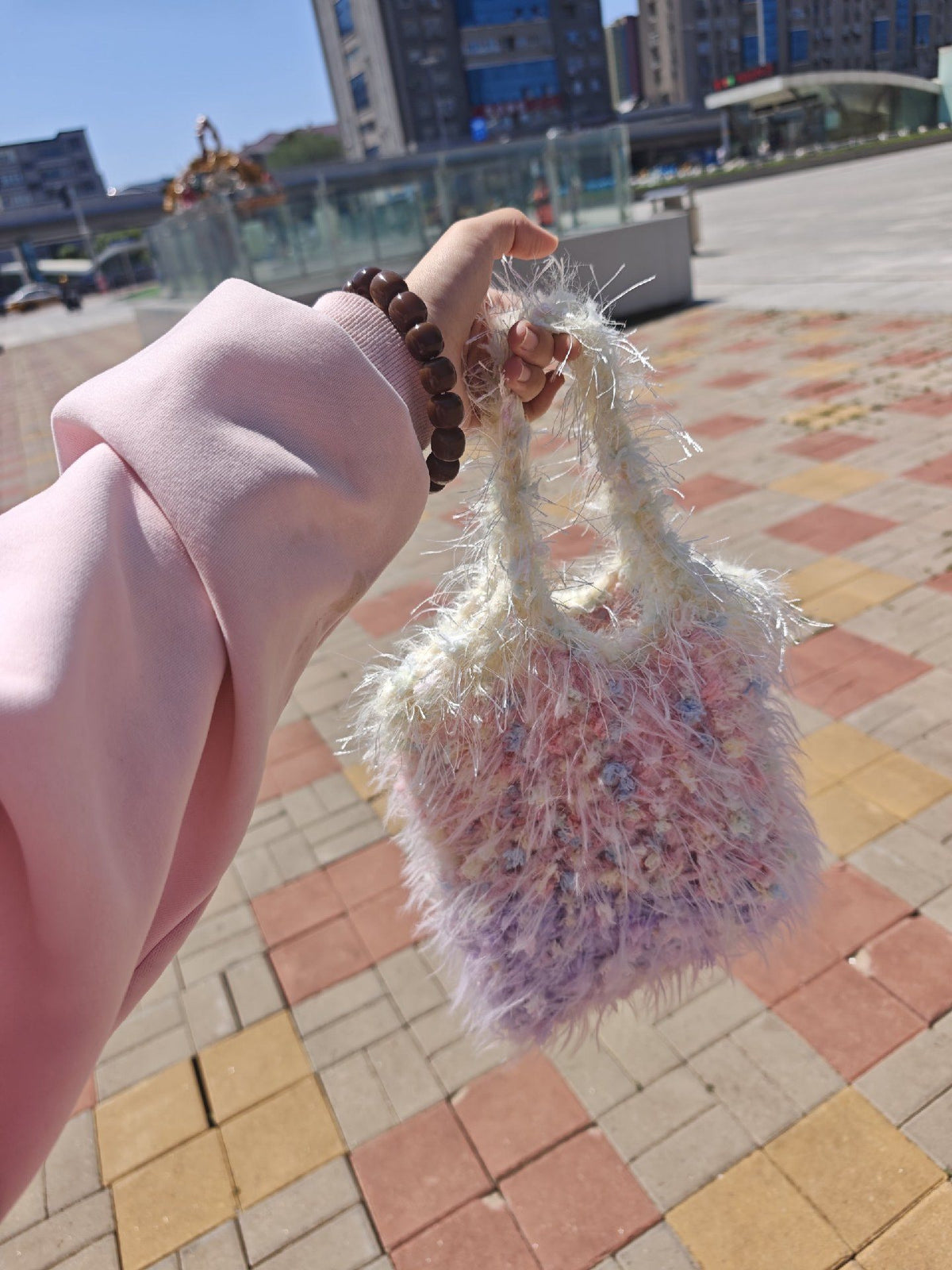 Real street view of a fluffy pastel crochet bag carried by hand