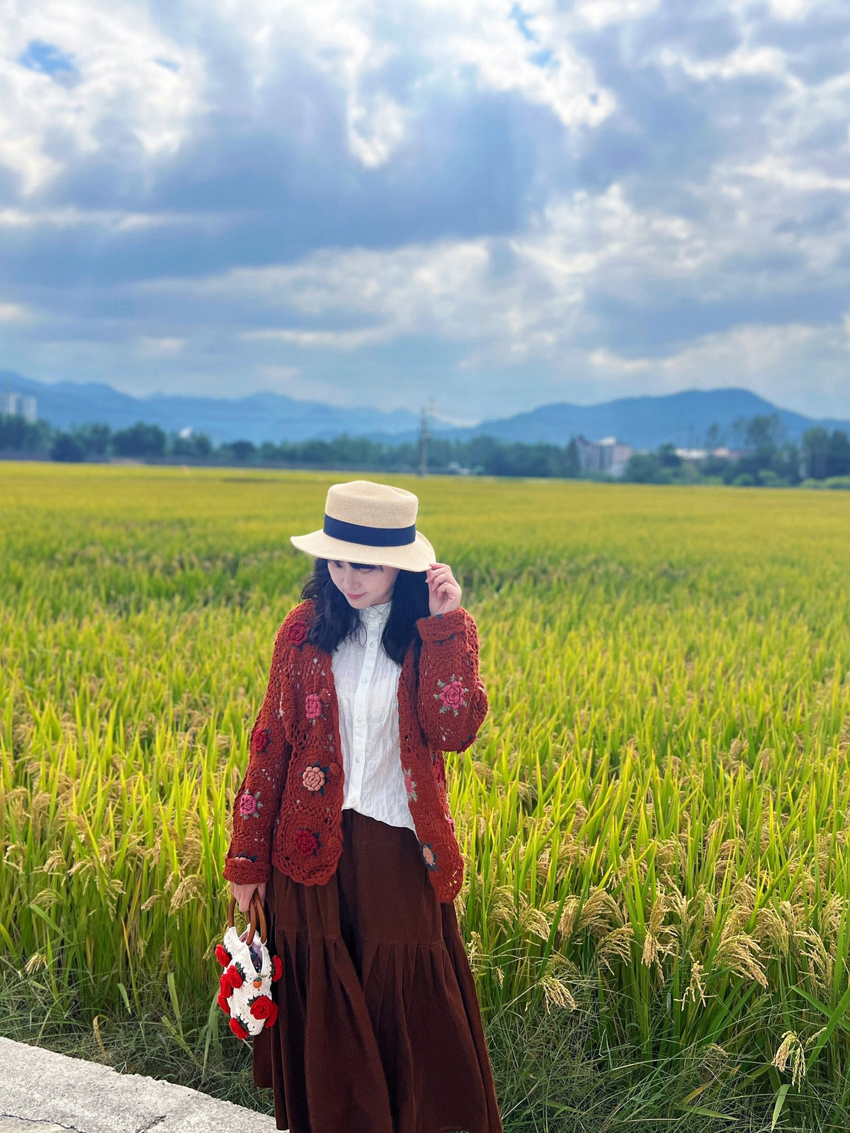 Real customer wearing crochet in the countryside with a floral handmade bag